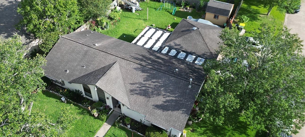 Aerial view of the same home before replacement, with weathered dark shingles and an aging low-slope section