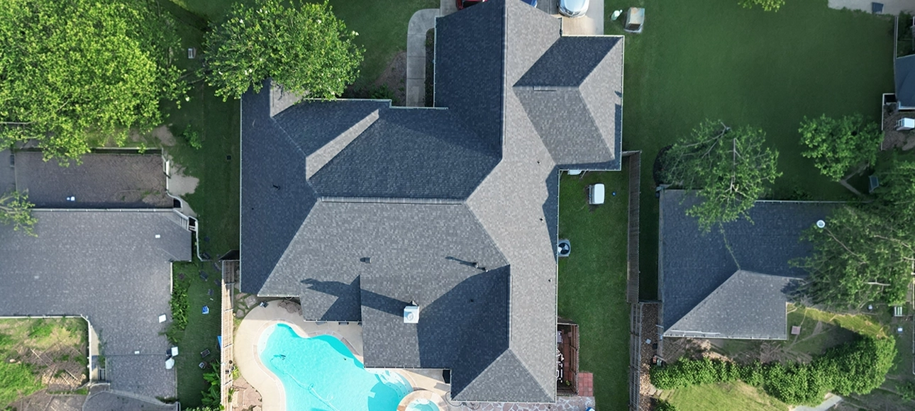 Top-down aerial view of a large home with a pool and a new charcoal gray shingle roof